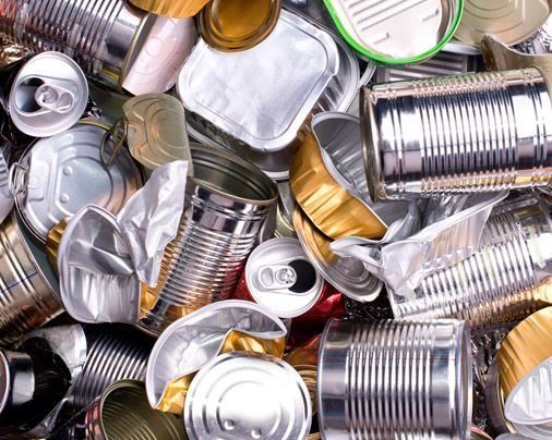 Montón de latas vacías de aluminio y hojalata, plateadas y doradas, apiladas muy juntas.