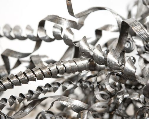 Primer plano de virutas de metal plateado enredadas, rizadas en espirales y tiras.