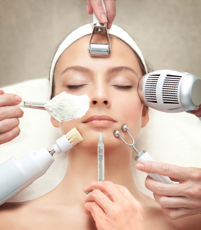 Mujer recibiendo tratamiento facial; varias herramientas rodean su rostro.