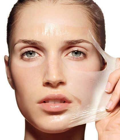 Mujer quitándose una mascarilla de la cara, mostrando una piel suave.