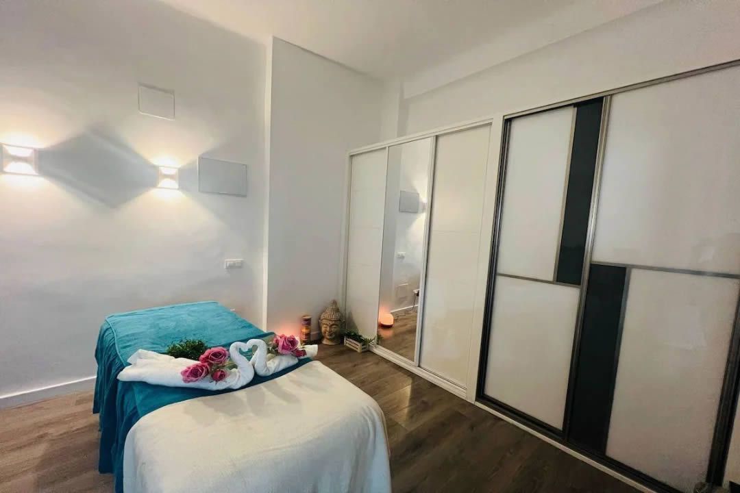 Sala de masajes con camilla, cubierta color turquesa y amplio armario.