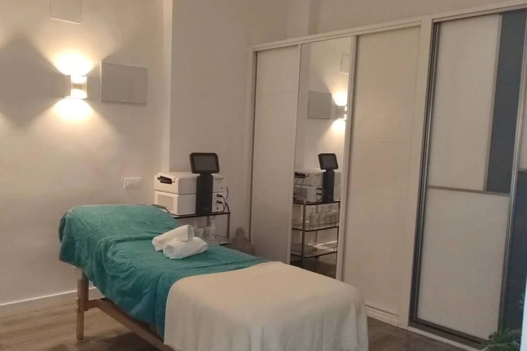 Sala de tratamientos de spa con mesa de masajes, gabinete y equipamiento.