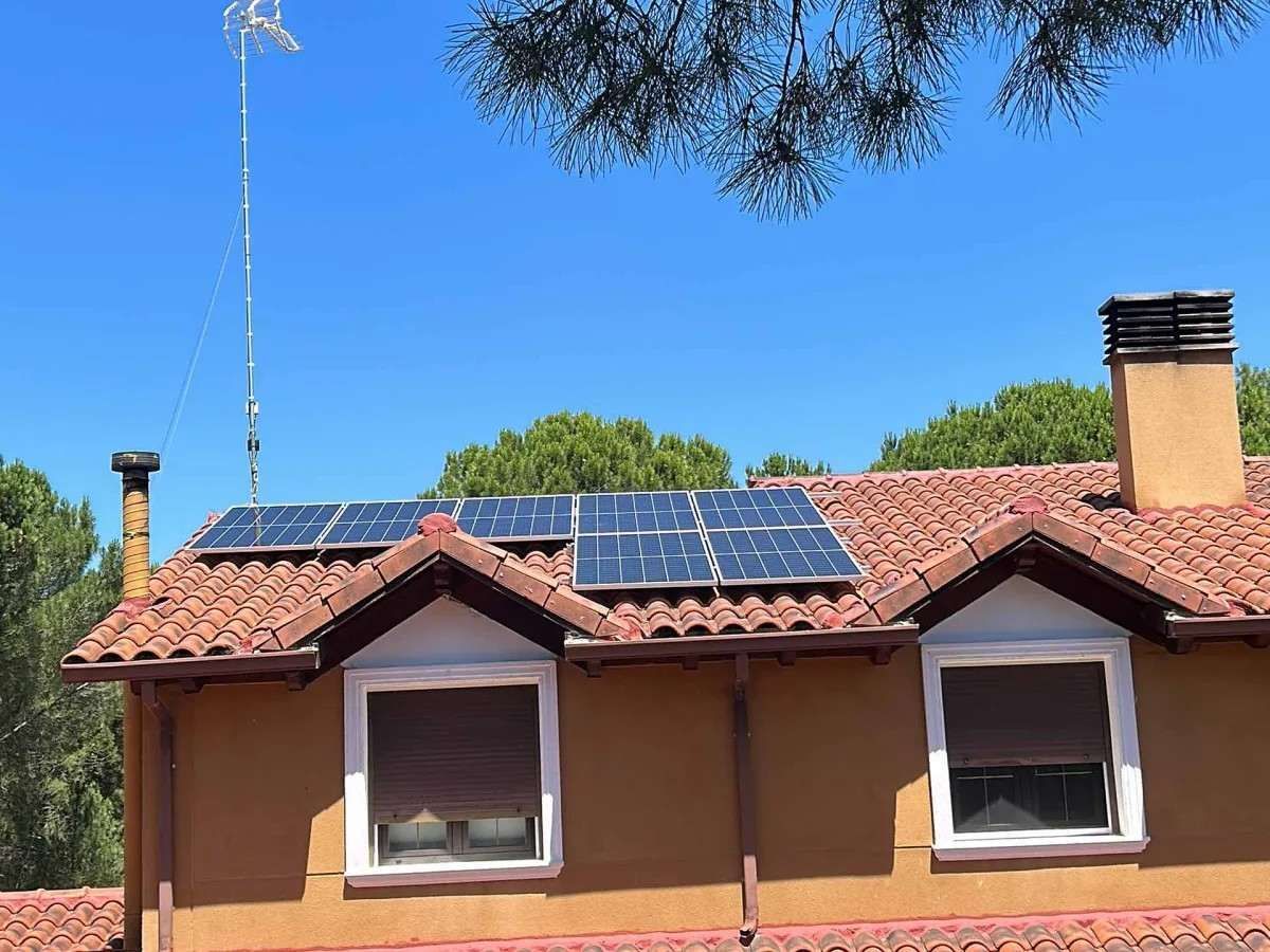 Tejado de una casa con paneles solares bajo un cielo azul despejado