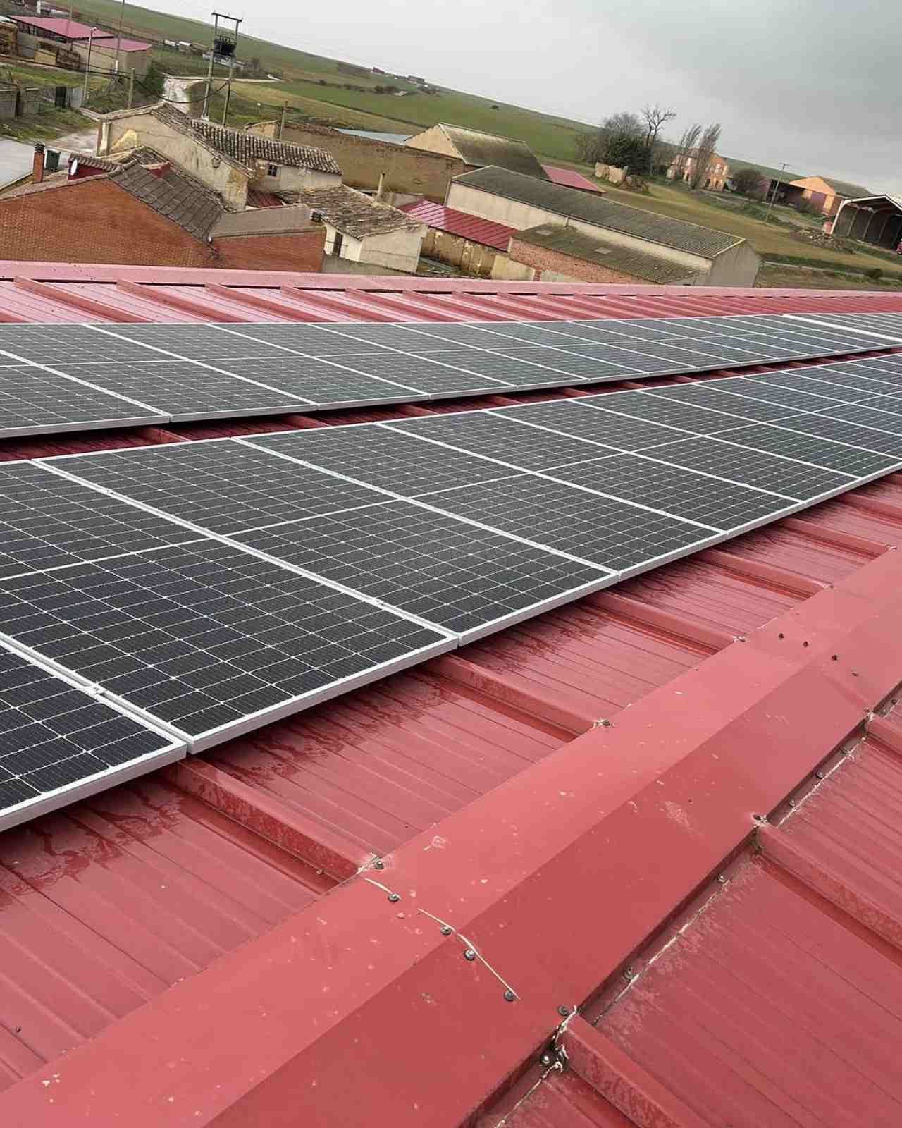 Paneles solares instalados sobre un tejado de chapa roja en un entorno rural