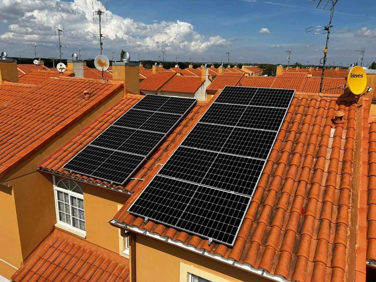 Azotea con dos grandes conjuntos de paneles solares sobre un tejado de tejas rojas bajo un cielo azul