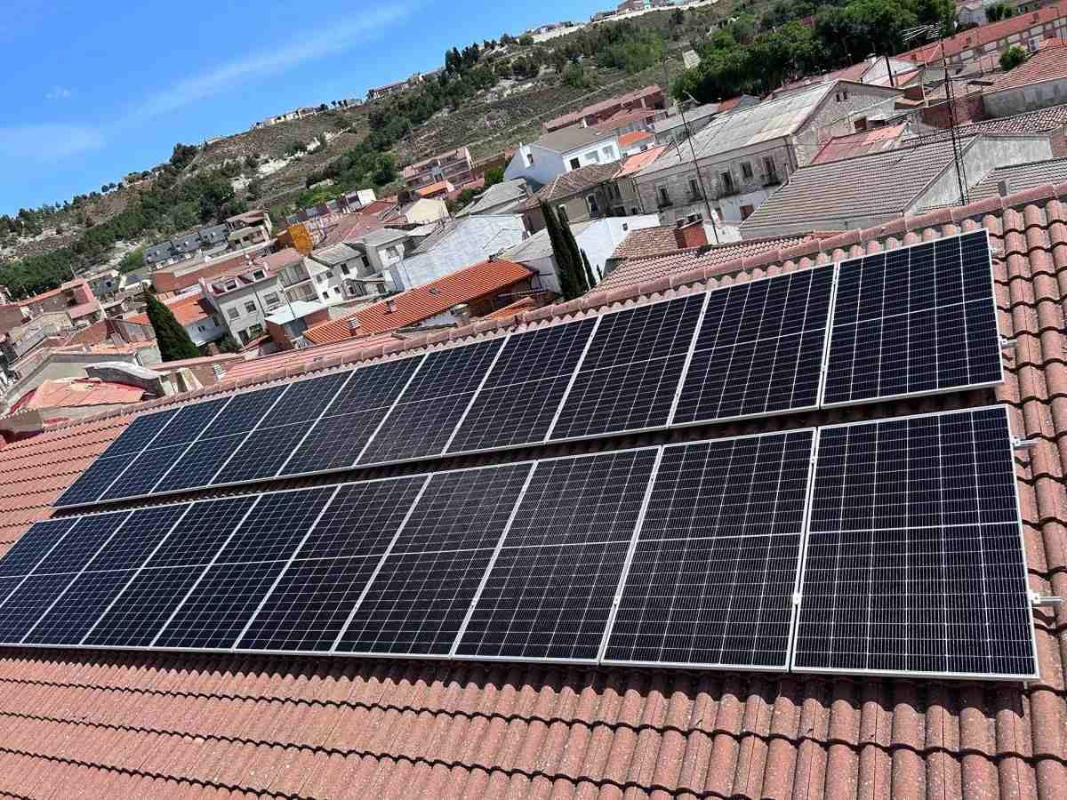 Paneles solares en un tejado de tejas rojas en un barrio de ladera bajo un cielo azul