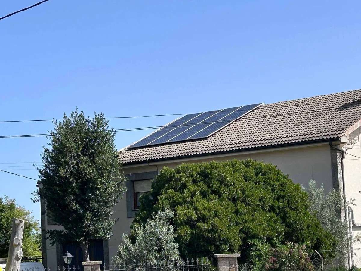 Casa con paneles solares en el tejado y un amplio jardín delantero bajo un cielo azul