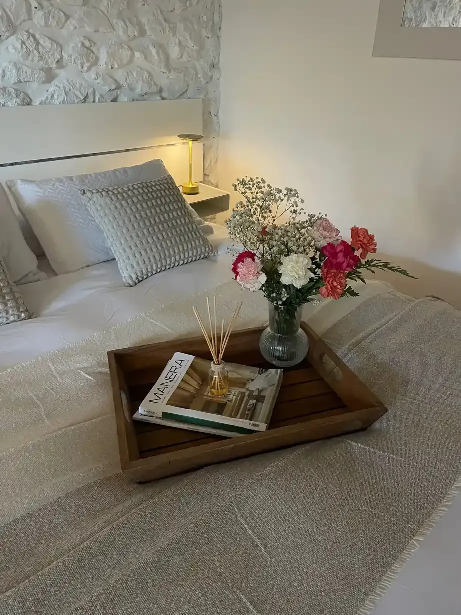 Estante blanco con toallas azules dobladas, decoración otoñal y una cesta de mimbre con flores.