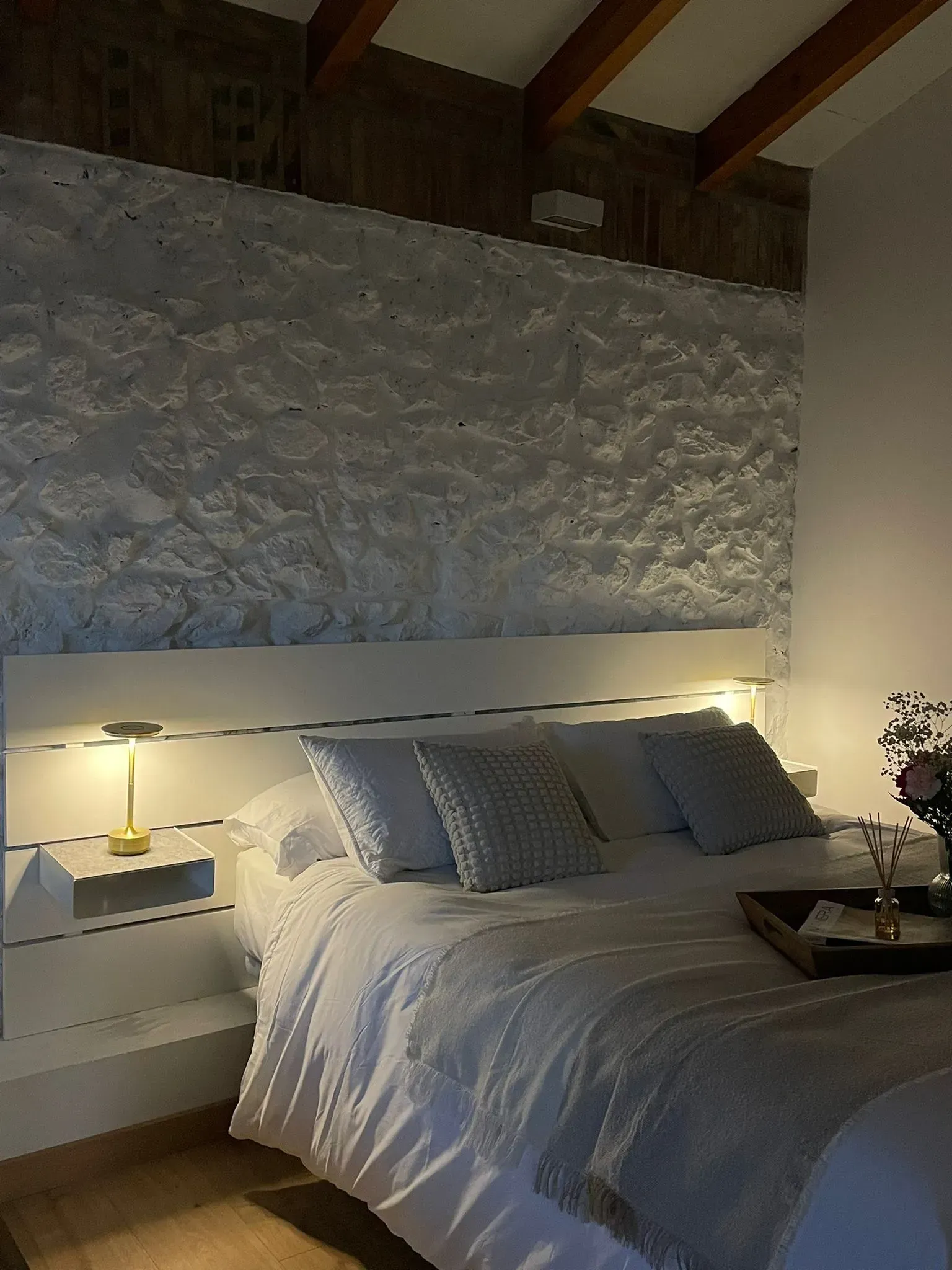 Acogedor apartamento tipo estudio con vigas de madera a la vista, gabinetes de cocina rojos y una cama.