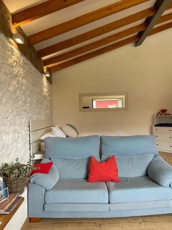 Sofá azul en una habitación con una pared texturizada blanca y un techo con vigas de madera.