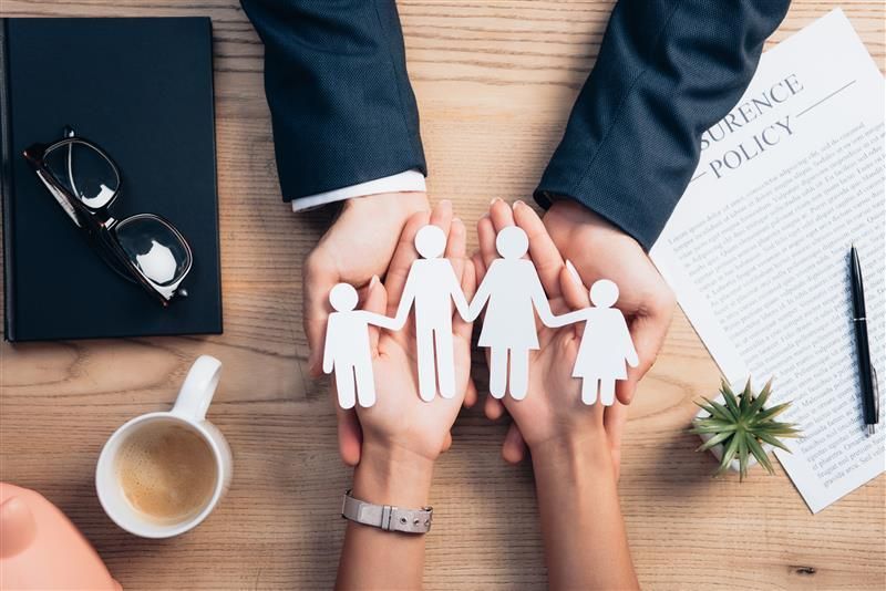 Famille en papier découpée posé aux creux des mais d'un couple.
