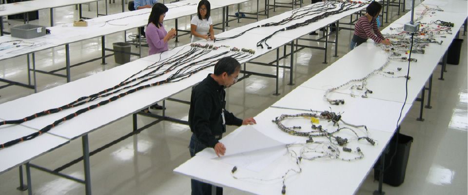 Un grupo de personas está trabajando en una gran mesa blanca.