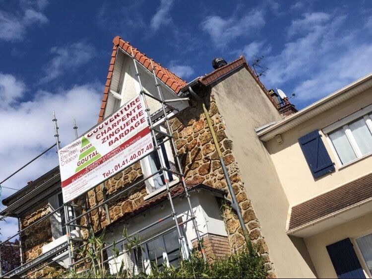 Façade en pierre d'une maison avec échafaudage doté d'une pancarte d'Artisan Goutal