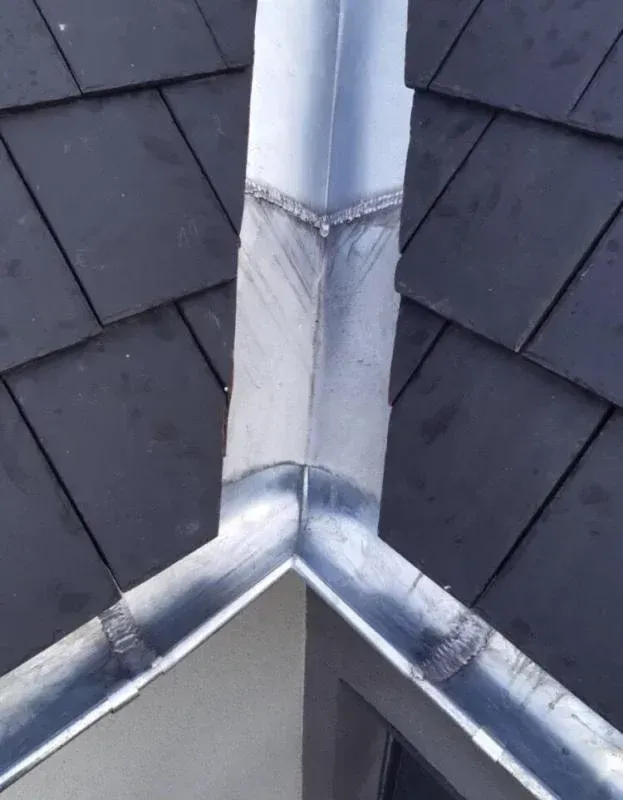 Chéneau et gouttières sur une toiture sombre d'une maison