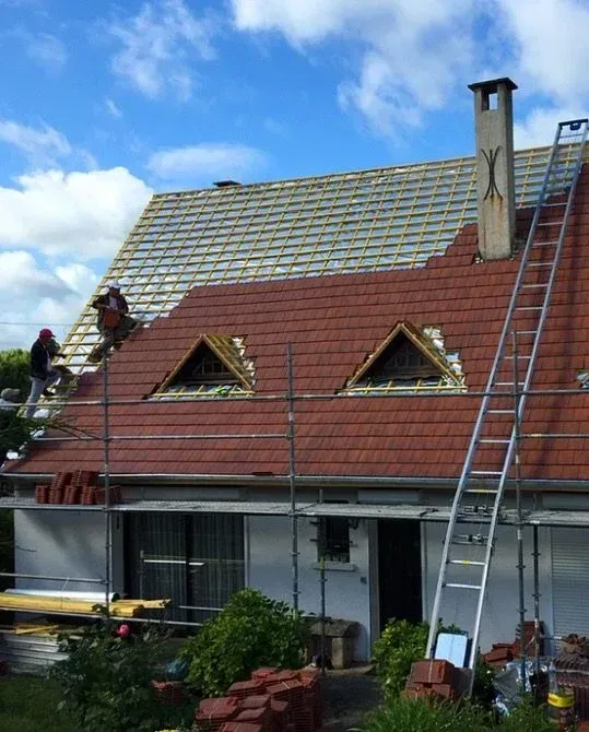 Professionnels sur une toiture sur laquelle ils remplacent les tuiles