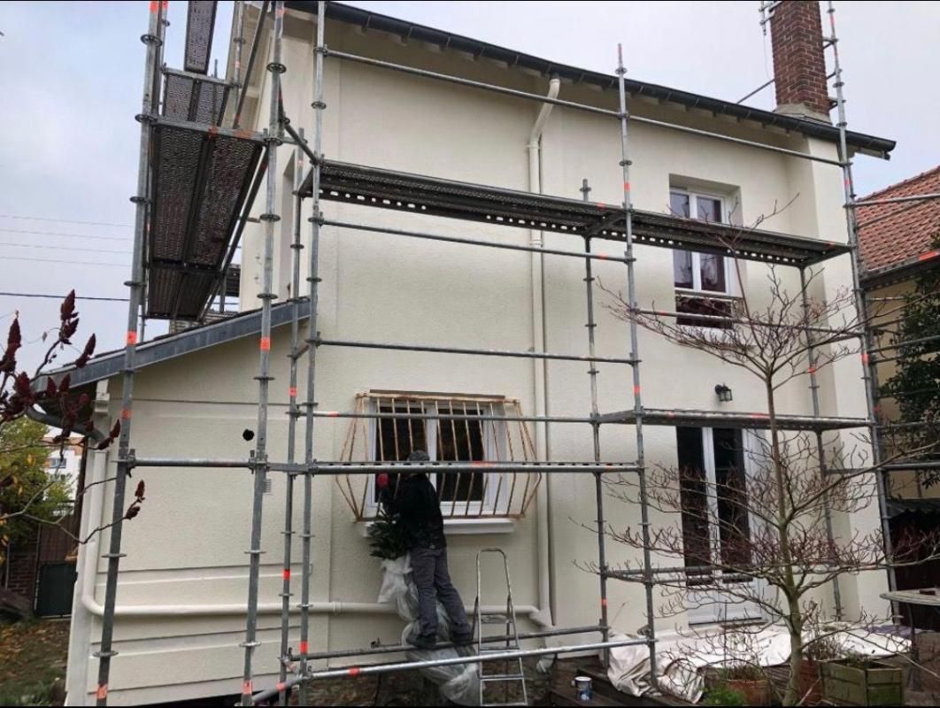 Professionnel rénovant la façade d'une maison équipée d'un échafaudage