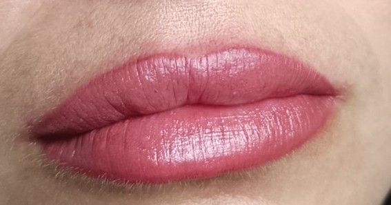 Primer plano de los labios de una persona, cubiertos con un lápiz labial de color rosa malva.