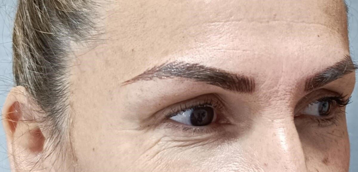 Primer plano de los ojos y las cejas de una mujer; cejas marrones; arrugas alrededor de los ojos.