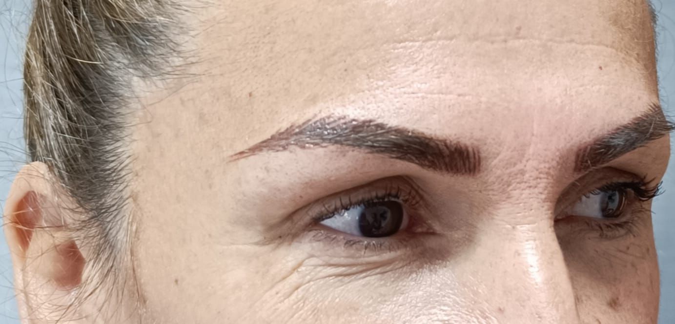 Primer plano del rostro de una mujer, cejas marrones y ojos oscuros, con arrugas alrededor de los ojos.