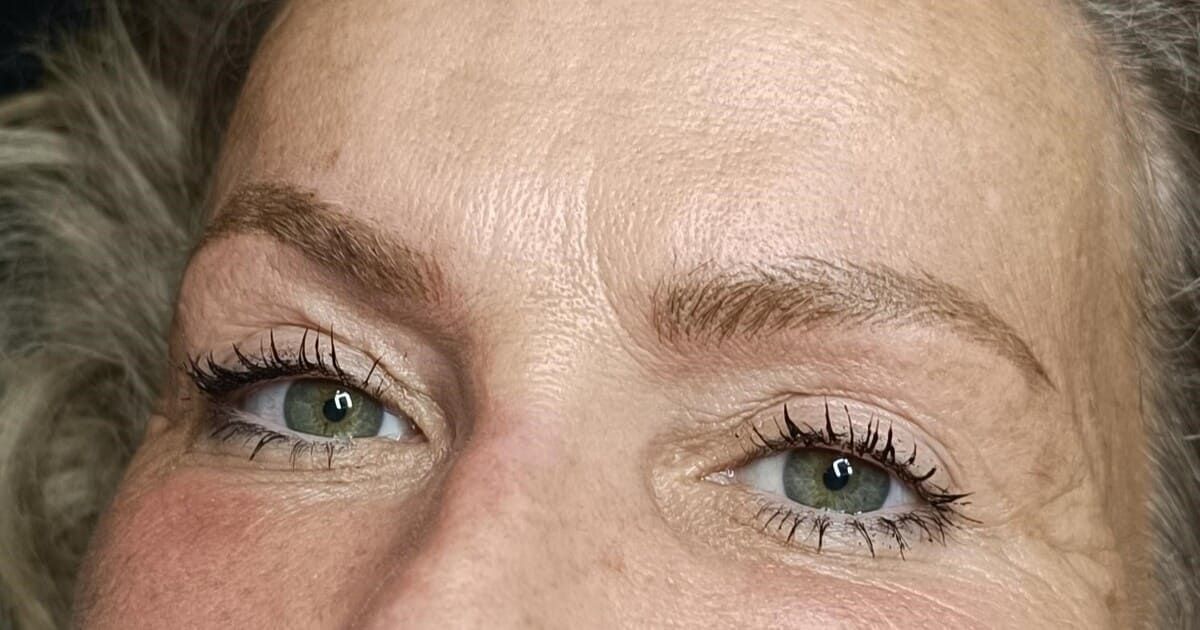 Primer plano de los ojos de una mujer, ojos verdes con rimel, cejas de color marrón claro.