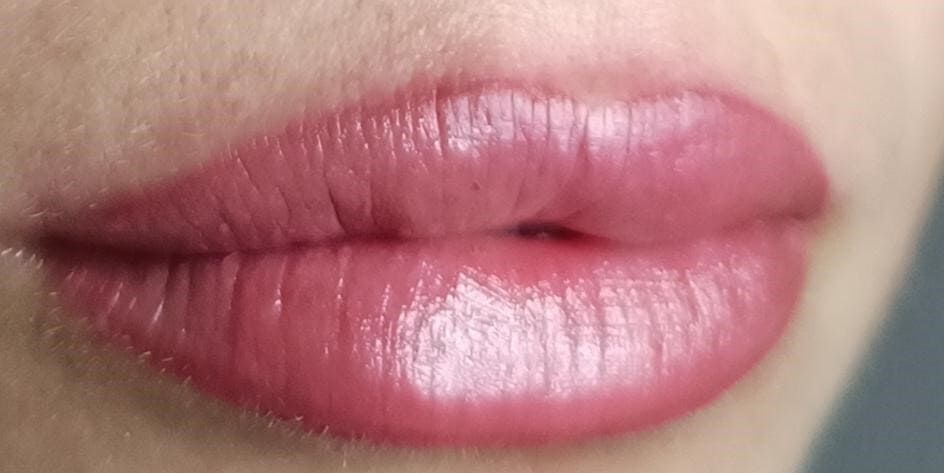 Primer plano de los labios de una persona, con un lápiz labial brillante de color malva rosado.
