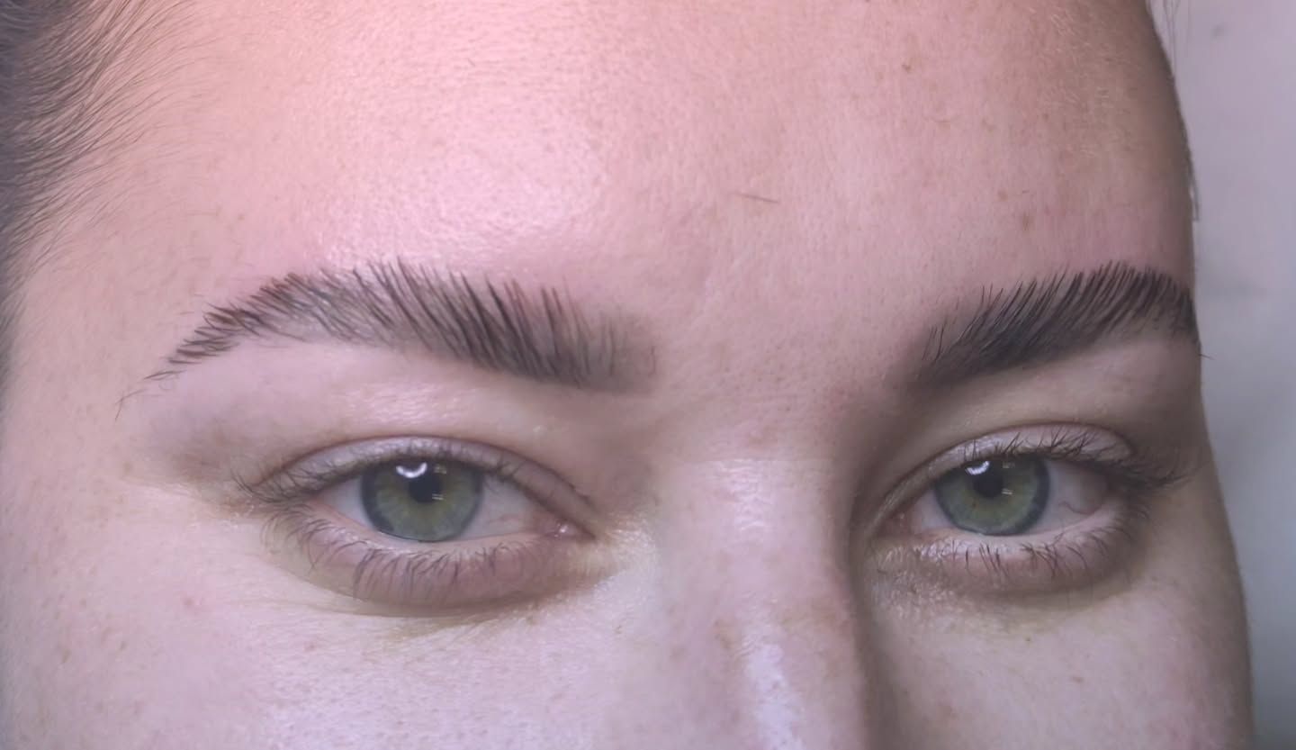 Rostro de mujer con ojos verdes y cejas bien depiladas. Piel pálida, primer plano.