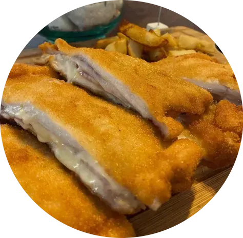 Un primer plano de un plato de comida con papas fritas al fondo.