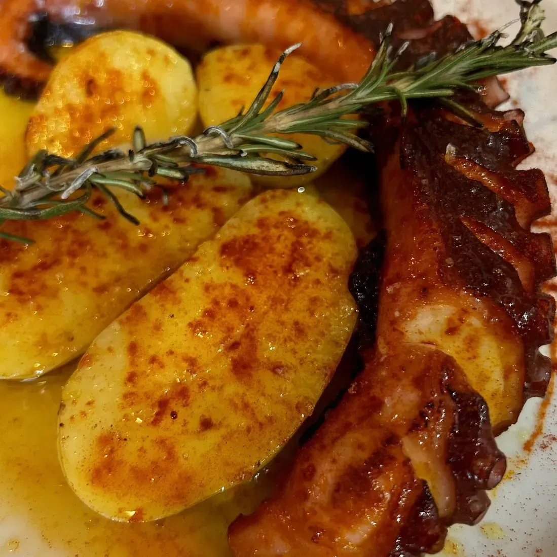 Un primer plano de un plato de comida con patatas y un pulpo.