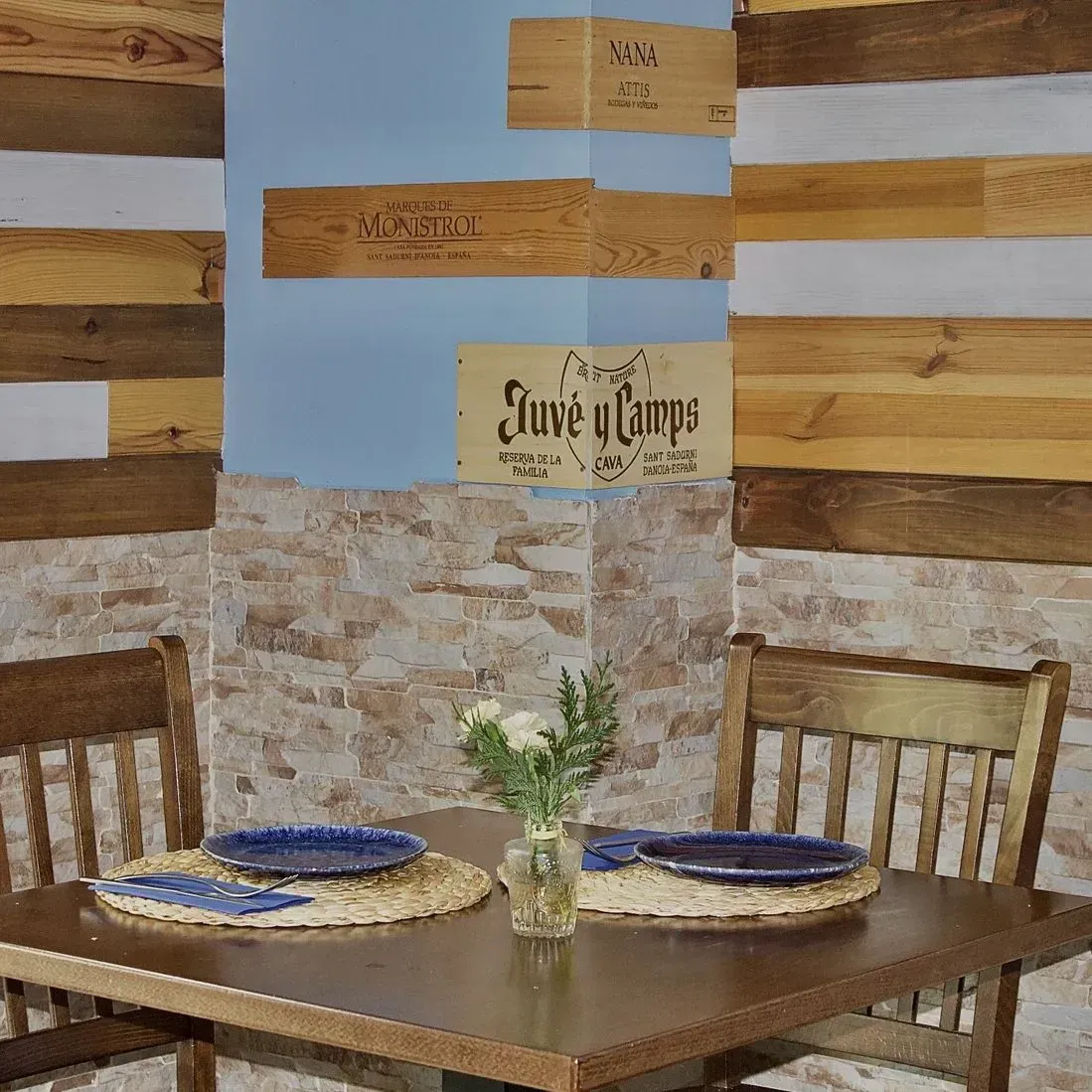 Una mesa de madera con platos y un jarrón de flores encima.