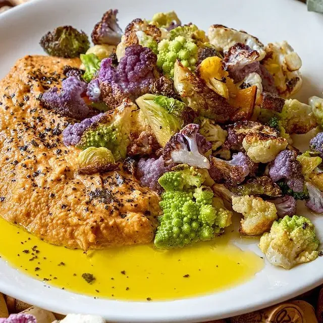 Un plato blanco cubierto con una variedad de verduras y salsa.