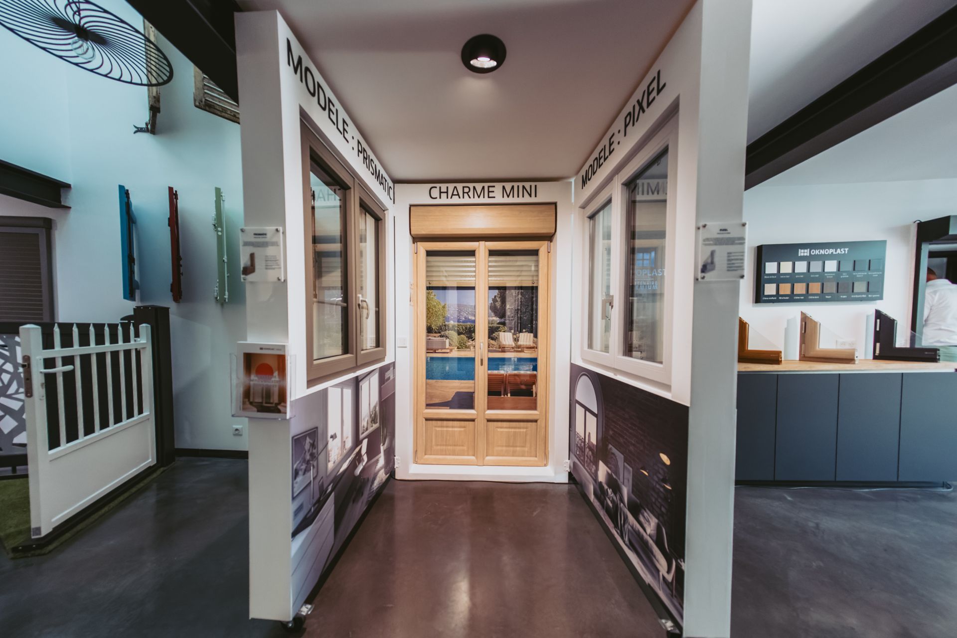 Une salle d'exposition avec des vitrines et une porte en bois centrée entre deux murs blancs portant des étiquettes d'information sur les produits.