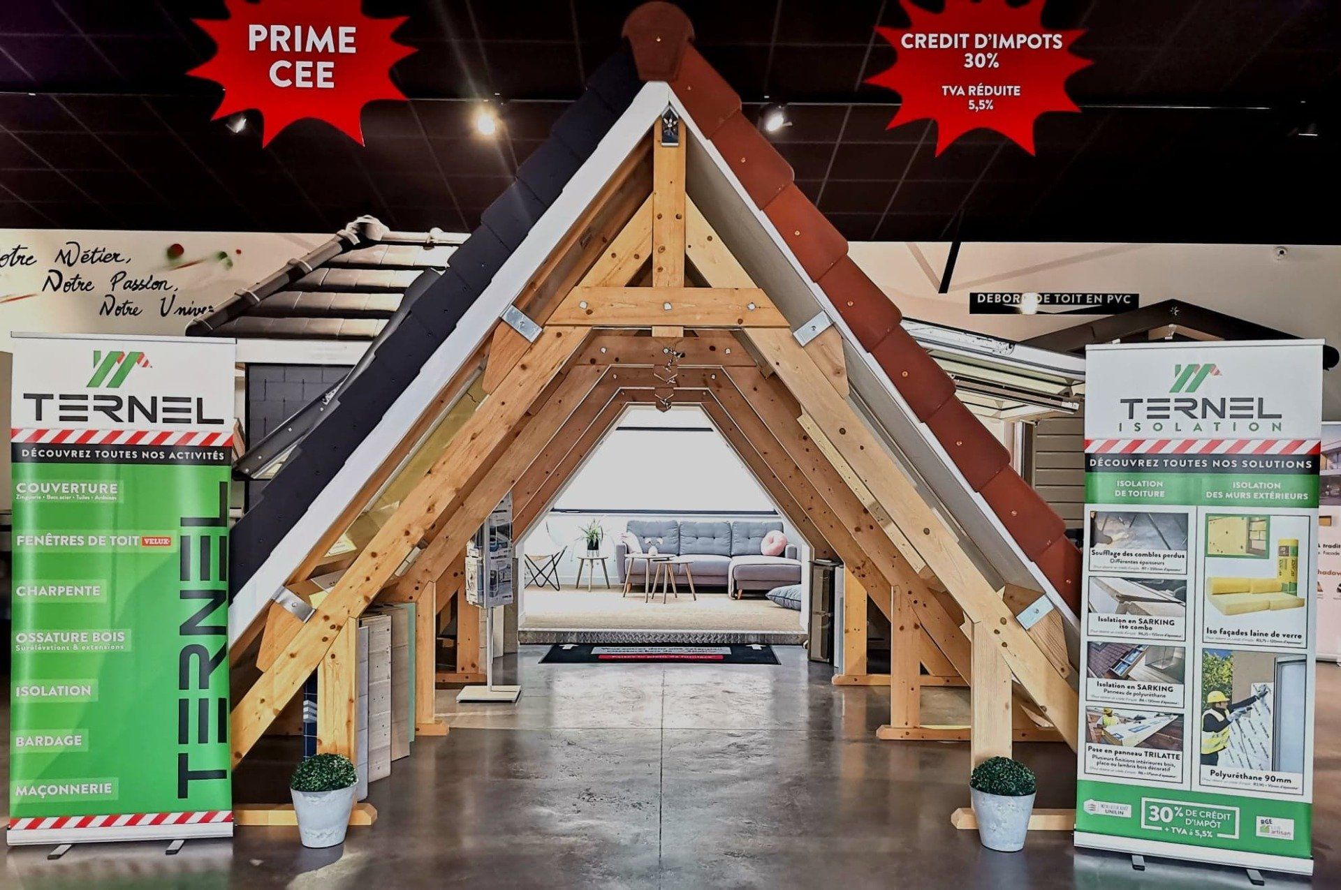 Une charpente triangulaire en bois présente des tuiles de toiture sur un stand de salon professionnel de la marque Ternel.