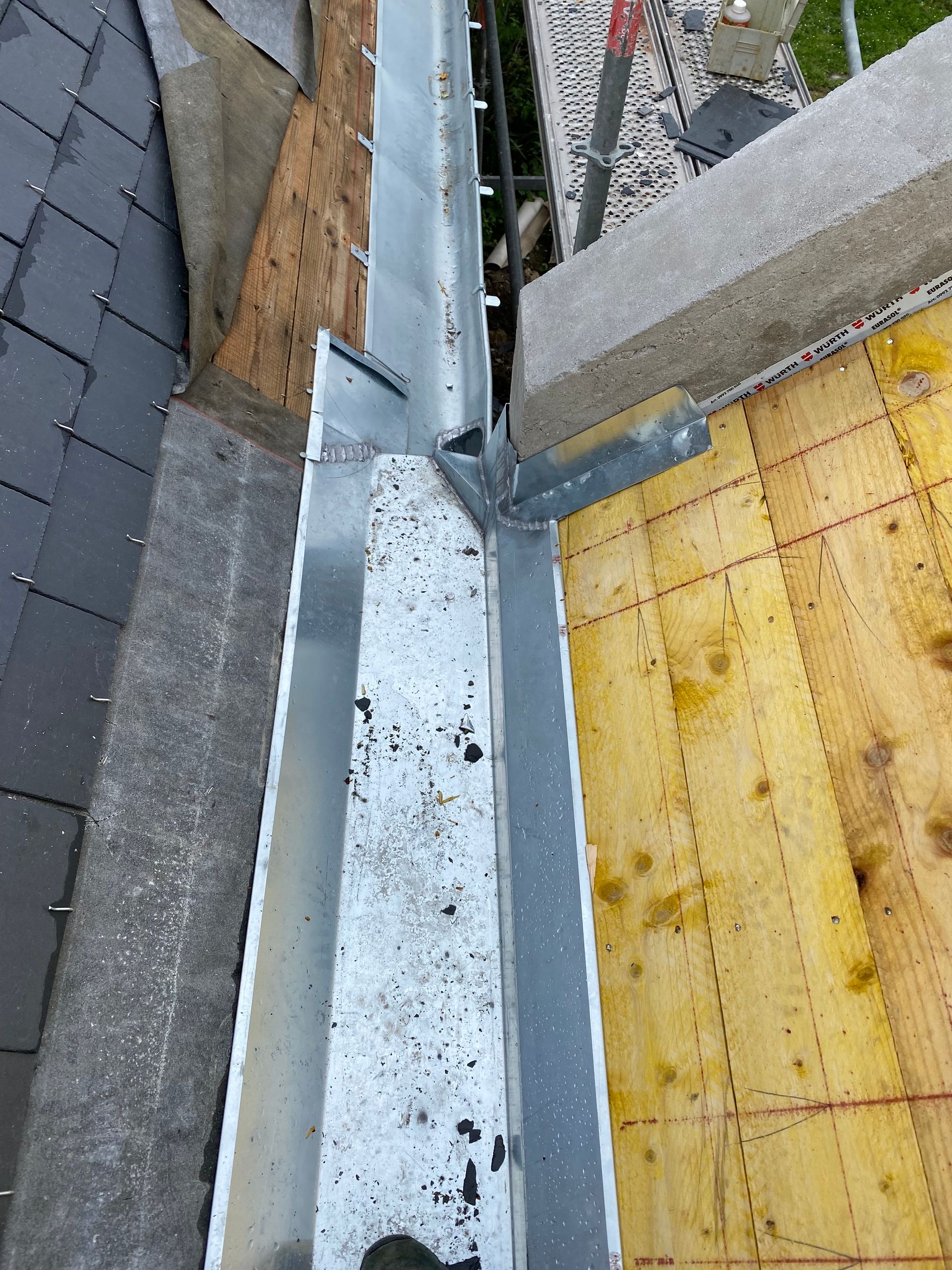 Gros plan sur le bord du toit avec solin métallique, bardeaux gris et sous-couche jaune sur l'extérieur d'un bâtiment