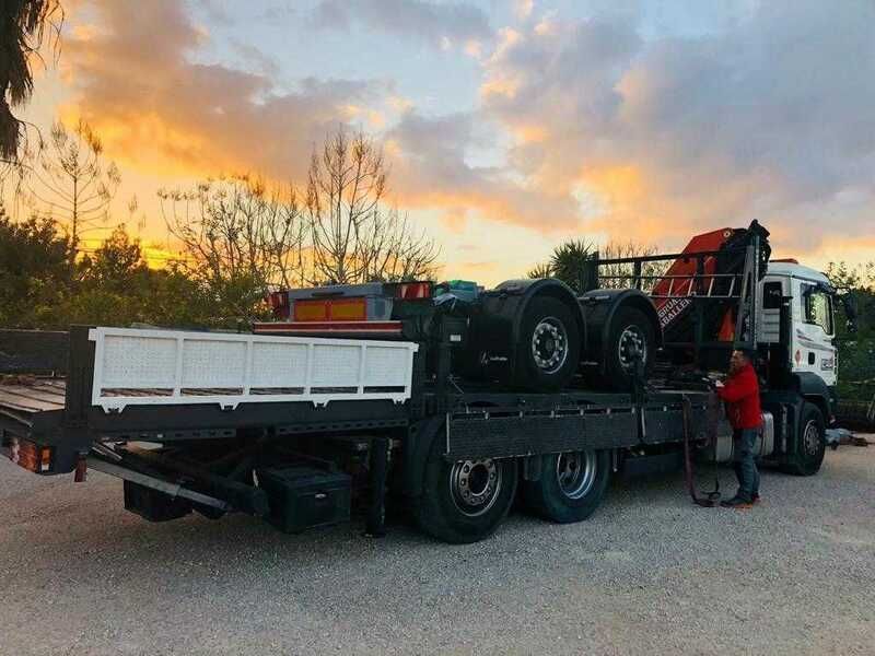 Un hombre está de pie junto a un camión que está cargado de neumáticos.