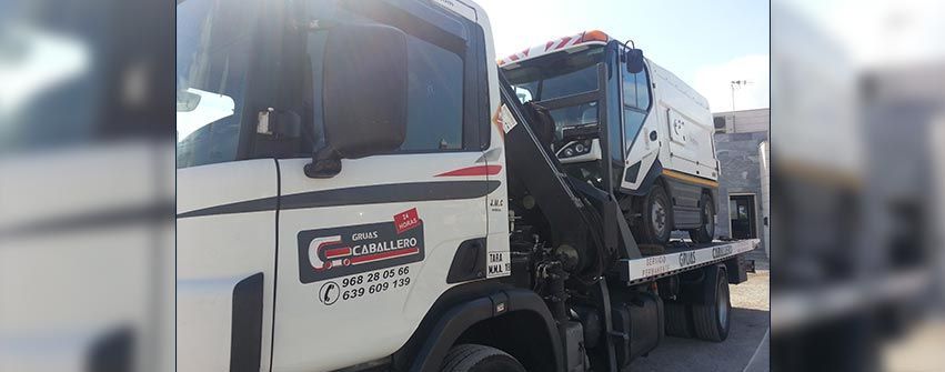 Una grúa blanca está estacionada al costado de la carretera.