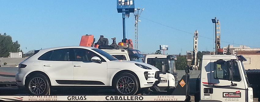 Un coche blanco está siendo remolcado por una grúa.