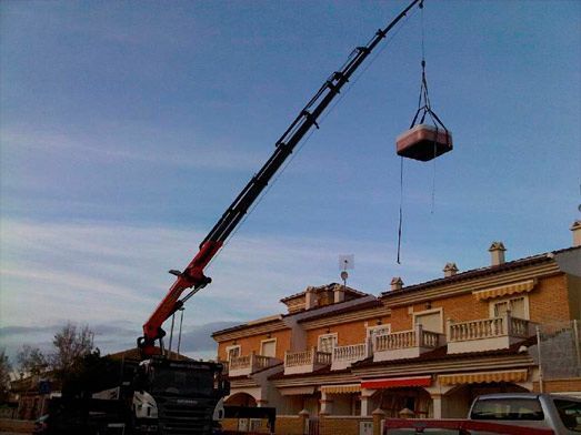 Una grúa está levantando un objeto grande sobre un edificio.