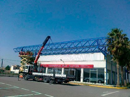 Un camión con una grúa acoplada está estacionado delante de un edificio.