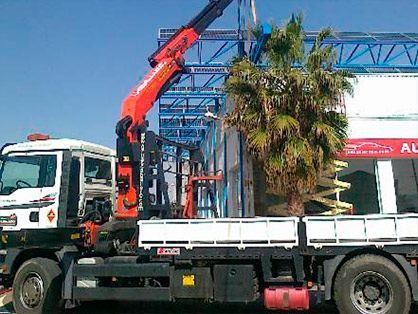 Un camión con una grúa en la parte trasera está estacionado frente a un edificio.