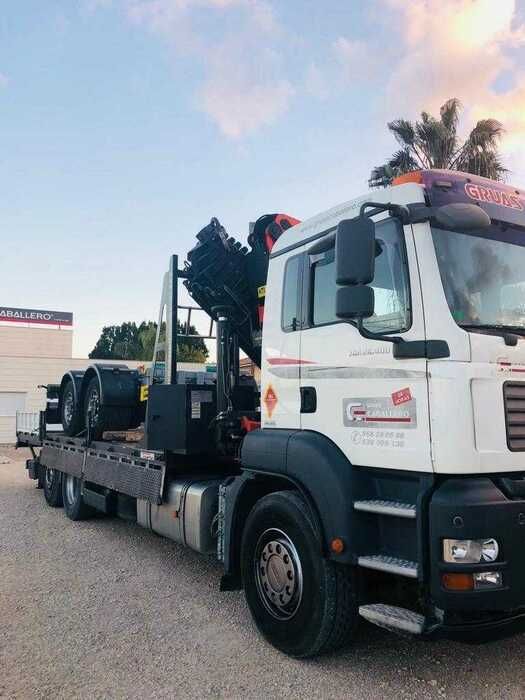 Un camión blanco con una grúa en la parte trasera está estacionado en un estacionamiento.