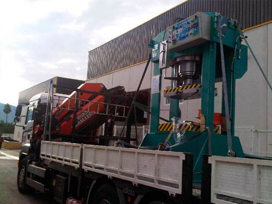 Un camión con una grúa en la parte trasera está estacionado frente a un edificio.