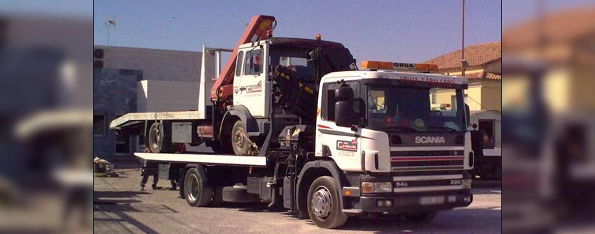 Una grúa blanca con una grúa en la parte trasera está estacionada en un estacionamiento.