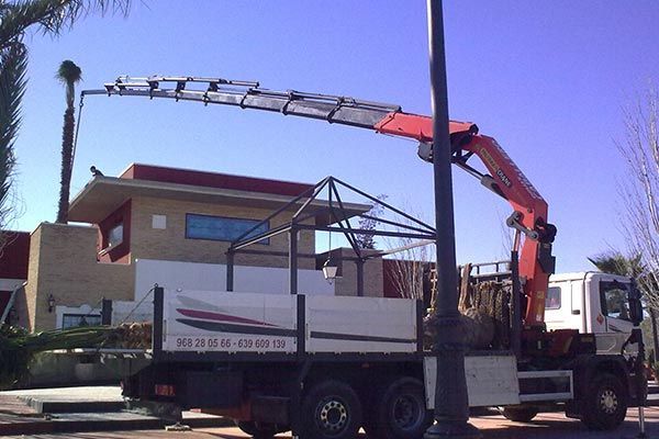 Un camión con una grúa en la parte trasera está estacionado frente a un edificio.