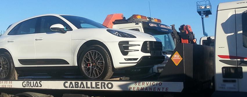 Un coche blanco está siendo remolcado por una grúa.