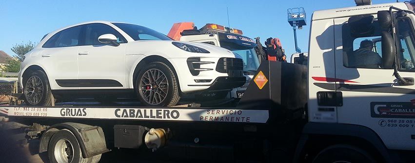 Un coche blanco está siendo remolcado por una grúa.