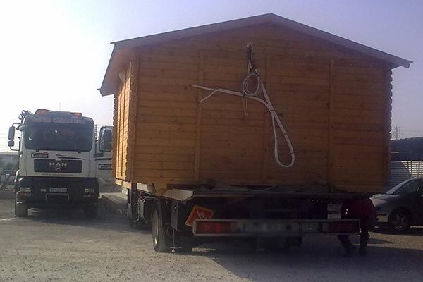 Un camión de carga transporta una pequeña casa de madera.
