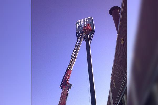 Una grúa está sentada encima de un edificio con un cielo azul de fondo.