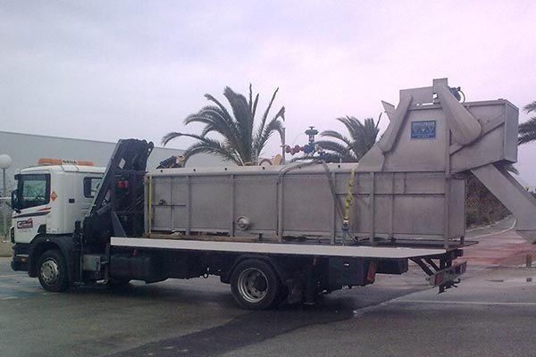 Un camión blanco con un gran contenedor en la parte trasera está estacionado al costado de la carretera.