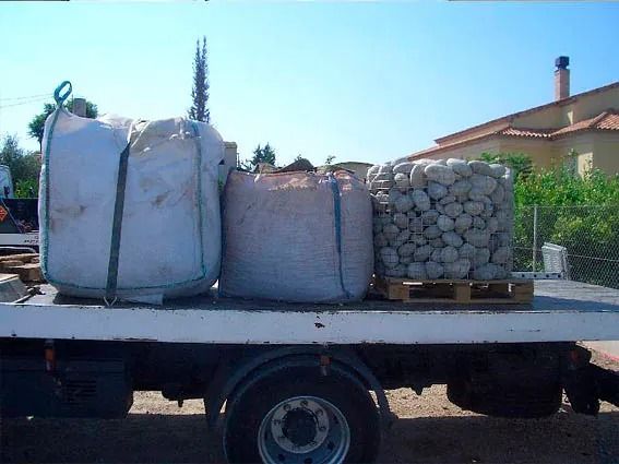 Un camión con bolsas de piedras en la parte trasera.
