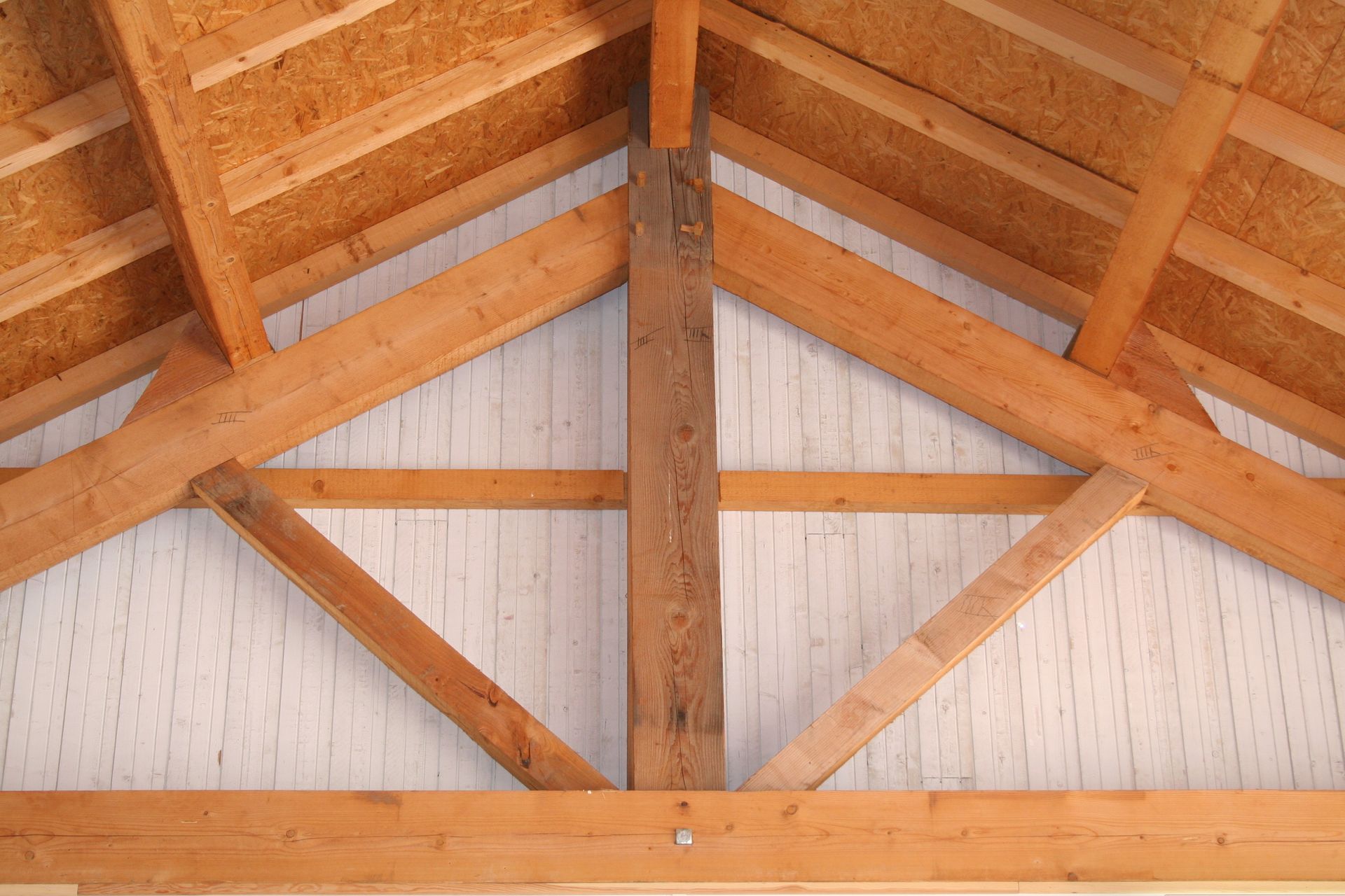 Charpente de toit en bois avec supports verticaux et inclinés, revêtement en panneaux OSB.